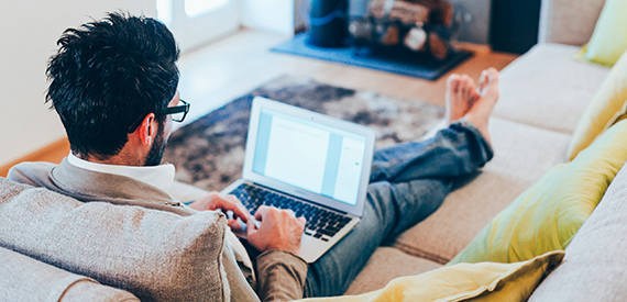 Man using laptop on couch.